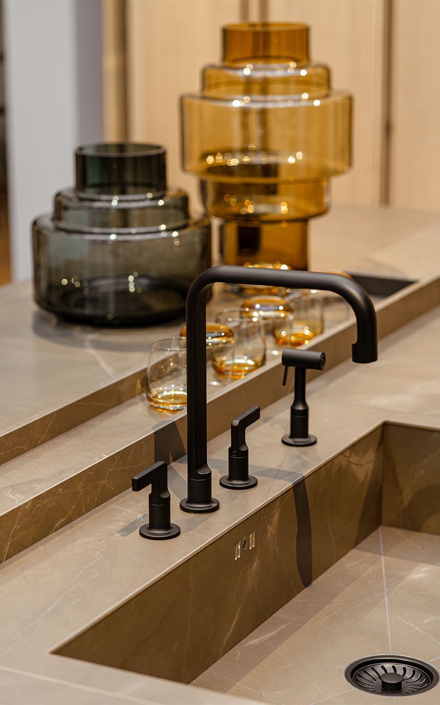 Waschbecken mit Schwarzen Armaturen Ein Steinwaschbecken mit mattschwarzen Armaturen und einigen dekorativen Gäsern