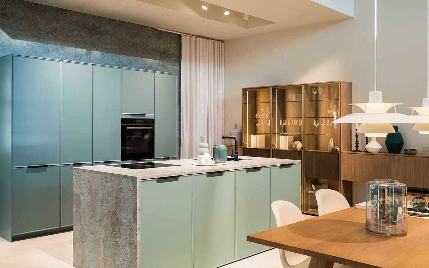 Türkise Küche mit Holzschrank Eine Türkise Küche mit Steinverkleideter Kochinsel und Holzschrank für Gläser