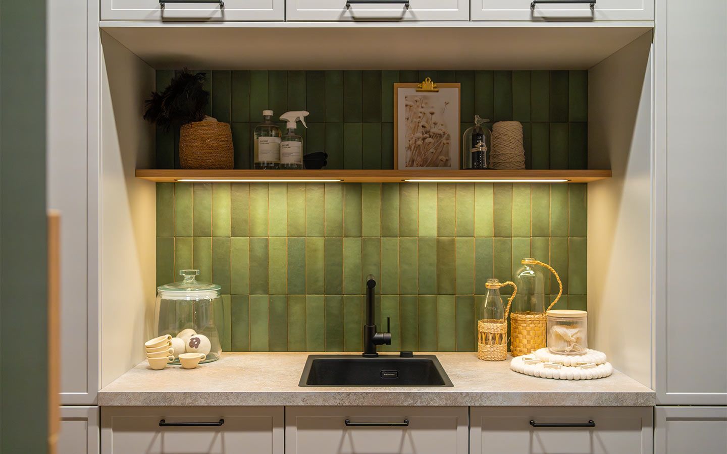 Waschbecken vor grüner Wand Ein schwarzes Waschbecken mit dekorativen Gläsern vor einer grünen Wand