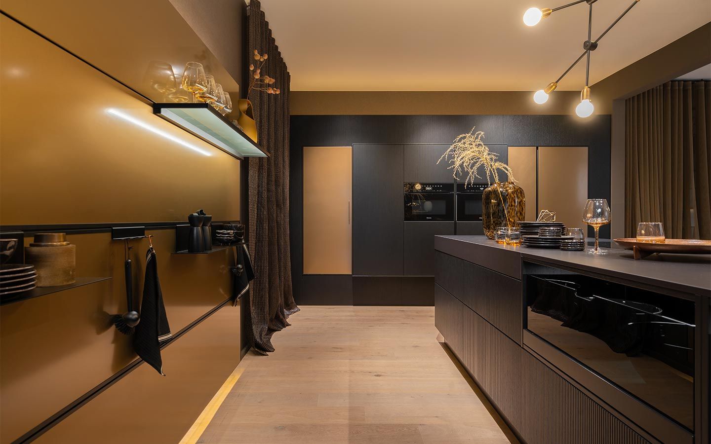 Schwarze Küche mit goldenen Wänden Eine edle schwarze Kochinsel mit Geschirr vor einer goldenen Wand