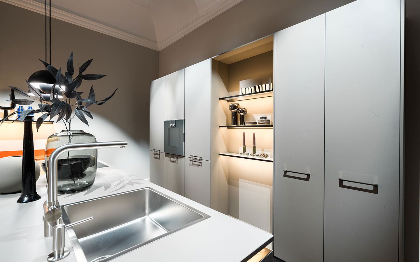 Beleuchtete Küche in schlichten Design Eine hell beleuchtete Küche mit grauen Schränken weißer Arbeitsplatte