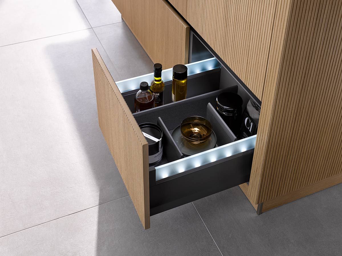Geöffnete Schublade mit Ölen und verschiedenen Schalen Geöffnete Schublade einer mit Holz verkleideten Kochinsel mit Ölen und verschiedenen Schalen