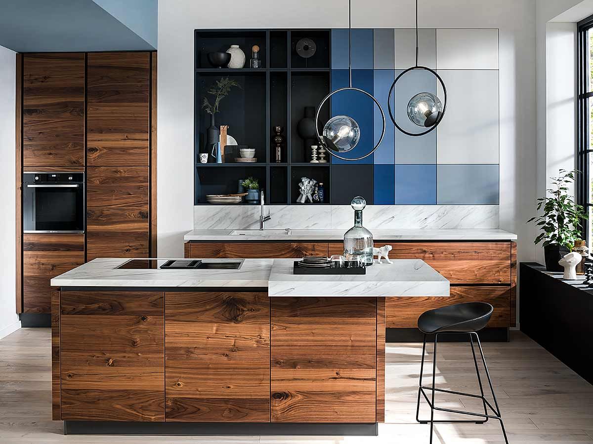 Holzküche mit blau-grauen Einbauschrank Eine mit dunklerem Holz verkleidete Küche mit Kochinsel und einem eingebauten Wandschrank