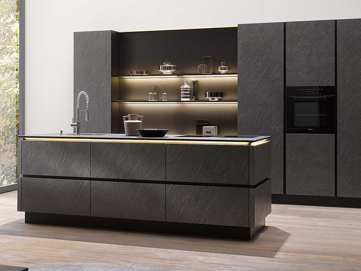 Moderne Küche in dunklem Steinfurnier Eine mit dunkelgrauem Steinfurnier verkleidete Küche mit Einbauofen