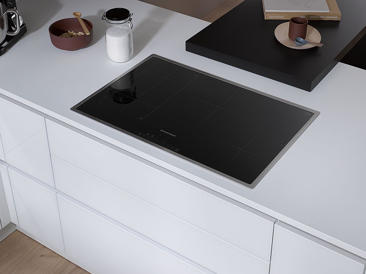Weiße Küche mit Tischplatte Eine weiße Küchenzeile mit integrierter schwarzen Tischplatte und einer etwas Geschirr herausgestellt